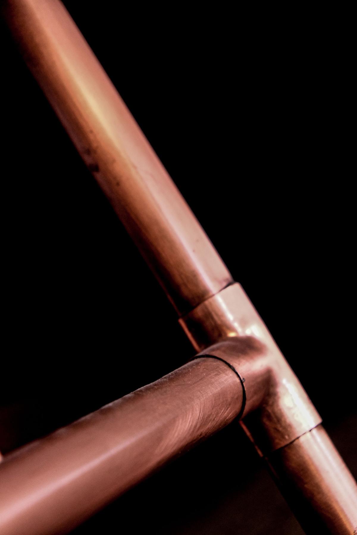 Copper pipe tee joint against a black background